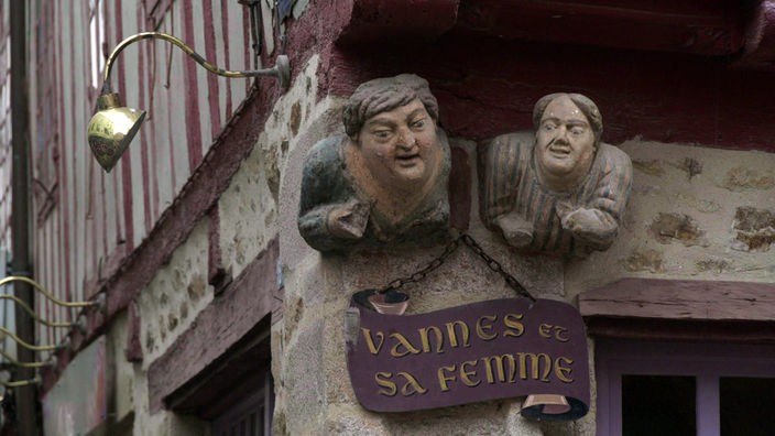 Holzfiguren von Mann und Frau an einer Hausfassade