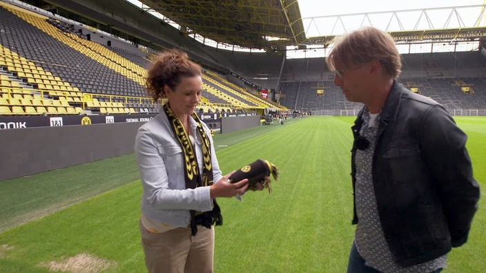 Anne Willmes und Peter Großmann stehen auf dem Rasen des BVB-Stadions