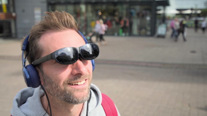 Daniel Aßmann mit einer VR-Brille und Kopfhörer