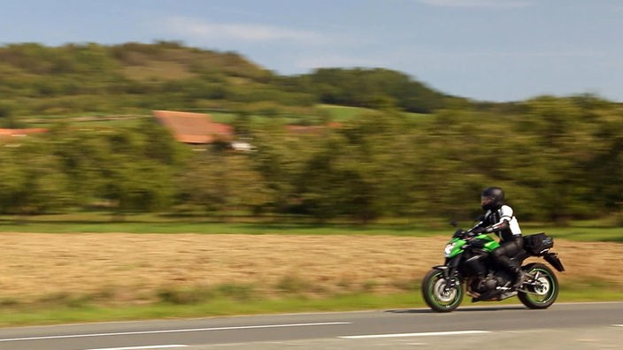 Andrea Grießmann fährt mit dem Motorrad, im Hintergrund vorbeifliegende Landschaft.