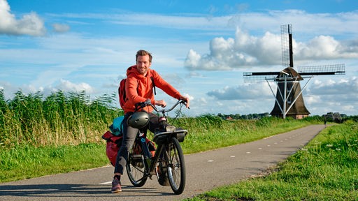 Daniel Aßmann auf einem "Solex" im niederländischen Friesland, im Hintergrund eine Windmühle