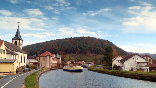 Ein Hausboot auf dem Rhein-Marne-Kanal, der hier durch ein kleines Dorf führt