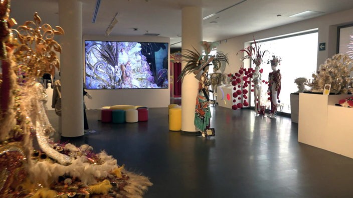 Ausstellungsraum mit kostümierten Puppen und Videomonitor