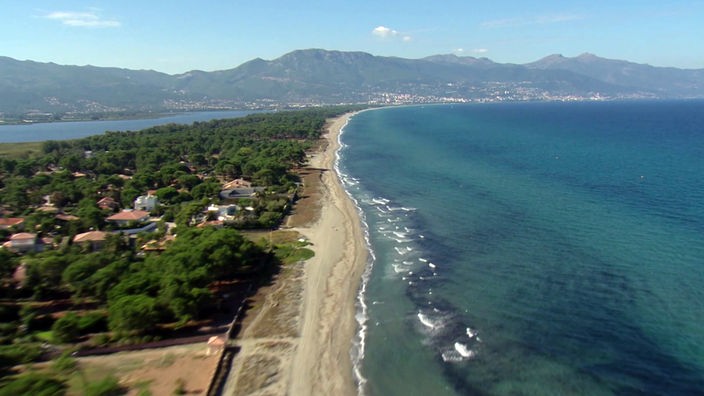 Korsikas Küste von oben mit kilometerlangem Sandstrand, im Hintergrund Küste mit Gebirge
