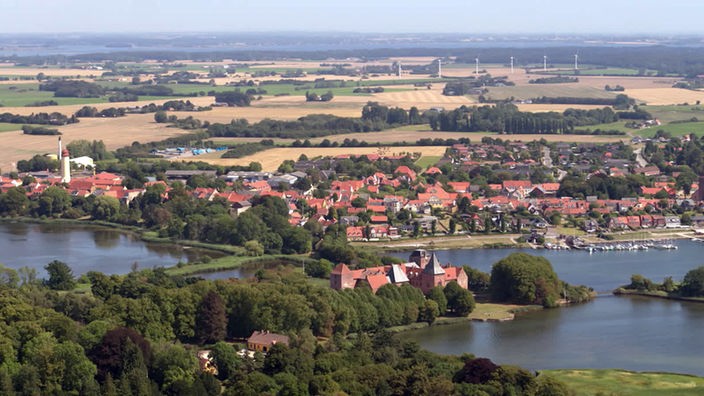 Luftaufnahme einer flachen Wald-Wiesen-Seen-Landschaft mit Ort Nysted