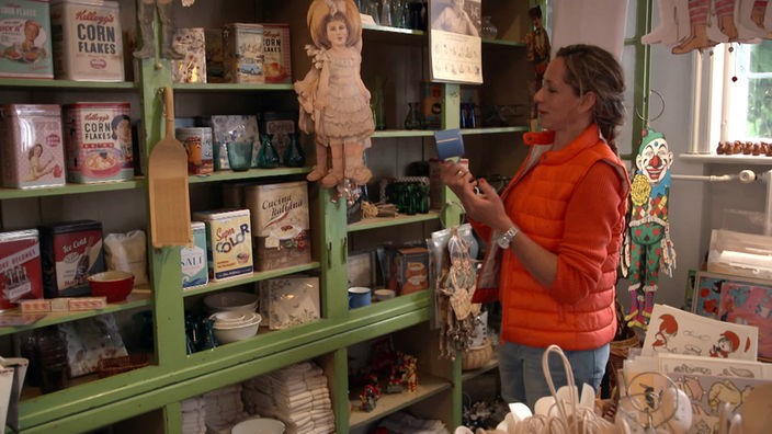 Tamina Kallert steht im Kaufmannsladen vor einem Regal mit Souvenirartikeln
