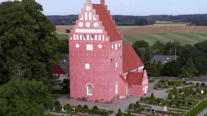 Rosafarbene Kirche aus Backstein mit einem mächtigen Turm