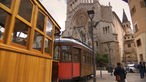 Historische rote Straßenbahn, im Hintergrund Fassade einer Kirche