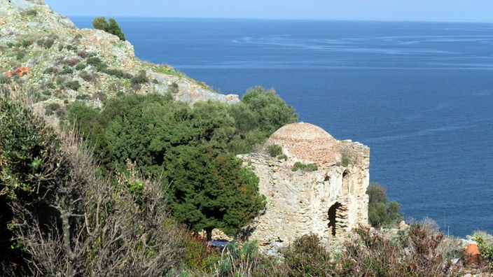 Kleine Ruine an einem Felshang über dem Meer