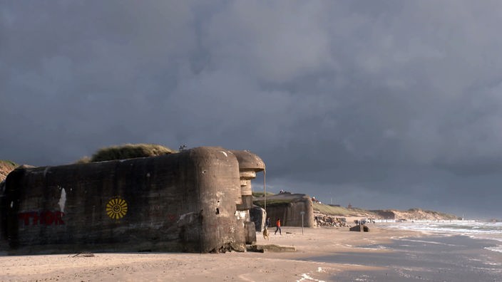 Bunker aus dem Krieg direkt am Sandstrand unter dunklem Gewitterhimmel