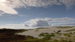 Dünenlandschaft mit blauweiß bewölktem Himmel