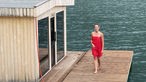 Tamina Kallert steht auf einer schwimmenden Holzplattform mit einem Saunahaus