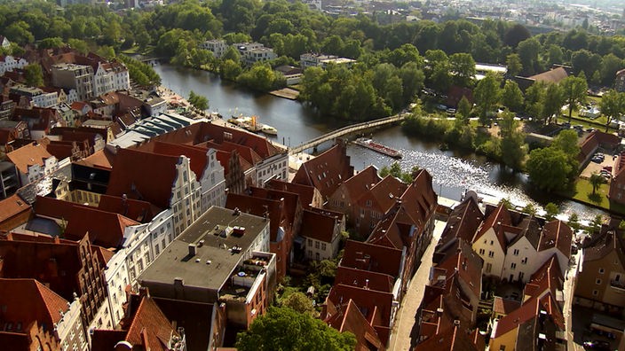 Luftaufnahme von Altstadthäusern, einem Fluss und Bäumen
