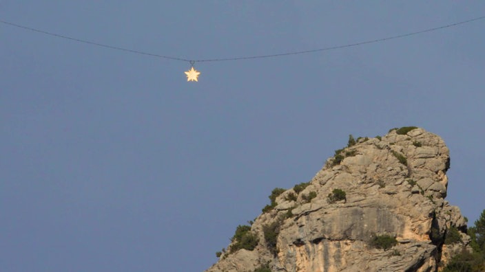 Ein goldglänzender Stern an einem Seil über Felsen