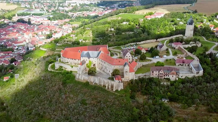 Große Burganlage auf einem Hügel, darunter ein Dorf