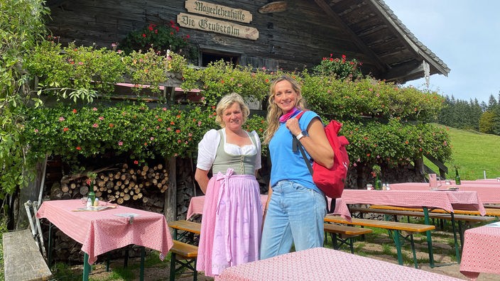 Tamina Kallert (r) und die Sennerin Lisi Matieschek stehen vor der Mayerlehenhütte auf der Gruberalm