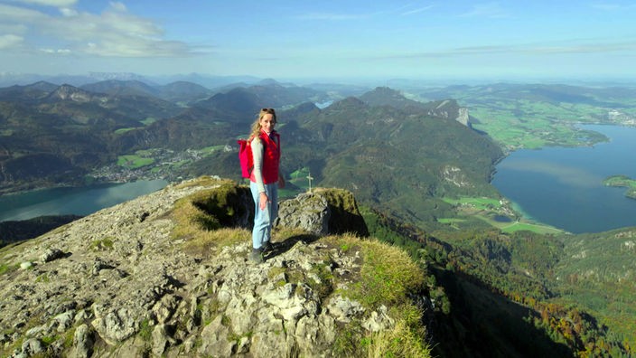 Tamina Kallert steht auf dem Gipfel des Schafbergs mit Blick auf die Bergseen.