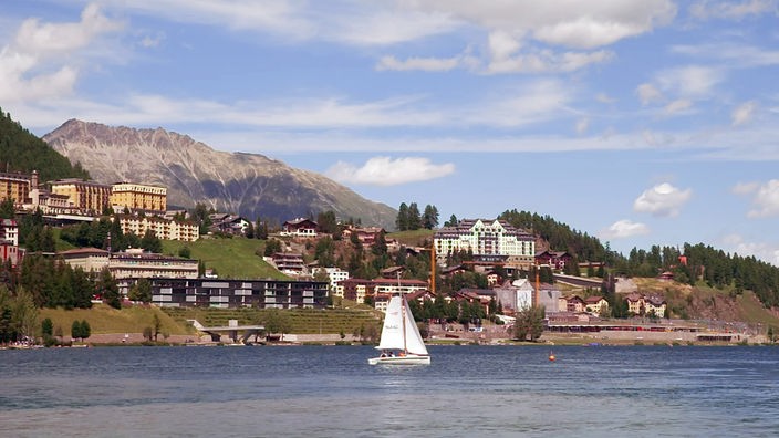 Blick über See mit Segelboot auf mehrere Hotelgebäude