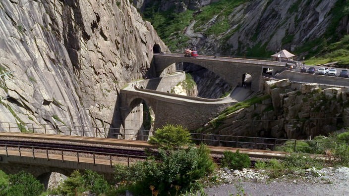 Brücke über ein schmales Tal führt in einen Tunnel in einer Felswand