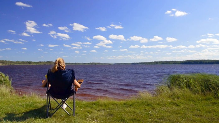Tamina Kallert sitzt in einem Campingstuhl und blickt auf den See Hulingen.