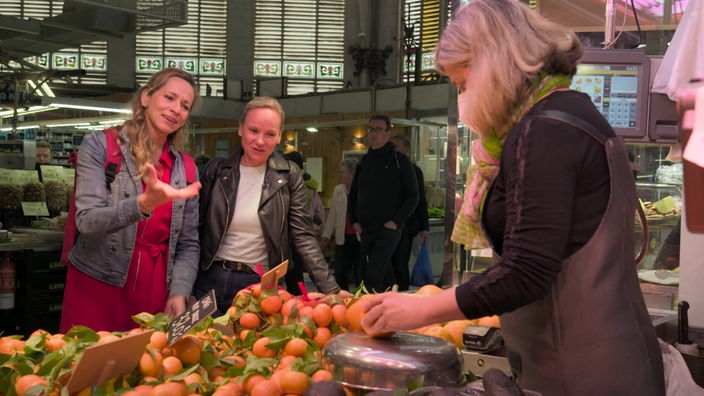 Tamina Kallert und eine Begleiterin an einem Obststand in der Markthalle "Mercardo Central" 