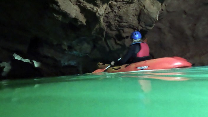 Jemand befährt mit einem Schlauchboot eine Höhle
