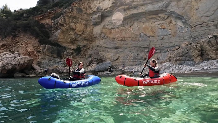 Tamina Kallert und eine weitere Person in je einem Packraft auf dem Wasser, im Hintergrund steile Felsküste