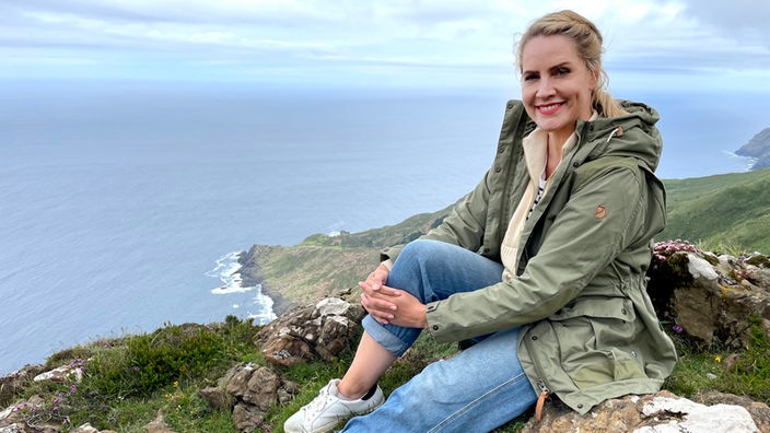 Judith Rakers sitzt an einer hohen Steilküste in Galicien