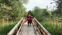 Tamina Kallert schiebt ihr Fahrrad über eine schmale Holzbrücke