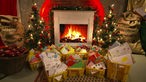 Mehrere Postkisten mit Wunschbriefen vor einem Kaminfeuer und zwei Weihnachtsbäumen