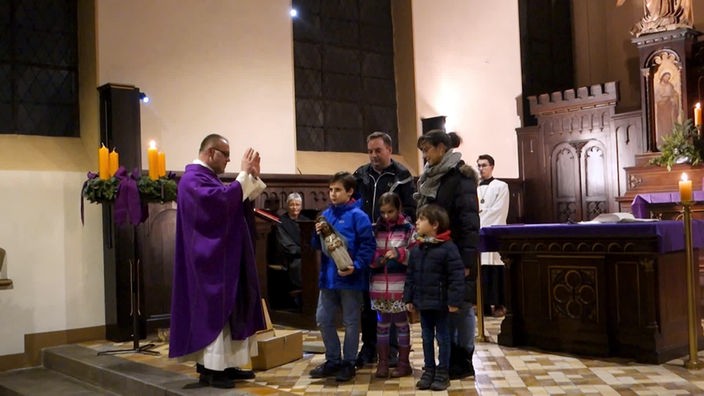 Familie mit Marienfigur und Pfarrer in einer Kirche