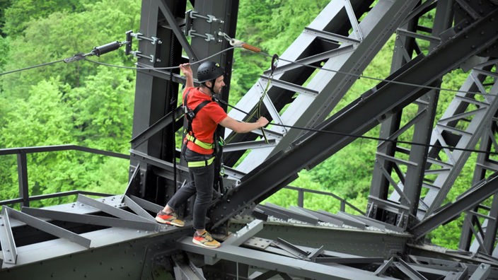 Daniel Aßmann mit Helm und Kletterausrüstung auf der Stahlbrücke