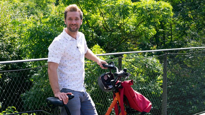 Daniel Aßmann steht neben einem Fahrrad