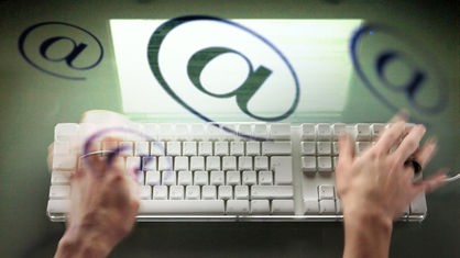 Eine Frau schreibt auf der Tastatur eines Computers, @ Symbole