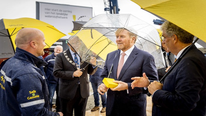 Willem Alexander steht mit einem Regenschirm in Rotterdam