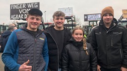 Lächelnd stehen die Jungbauern zusammen vor der Traktoren bei der Bauerndemonstration