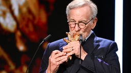 Steven Spielberg küsst nach der Verleihung seinen Goldenen Ehrenbären auf der Berlinale-Bühne.