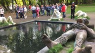Viele Menschen stehen an einem Brunnen mit mehreren Figuren