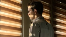 Ein Mann schaut aus dem Fenster - Szene aus "Burning Days"
