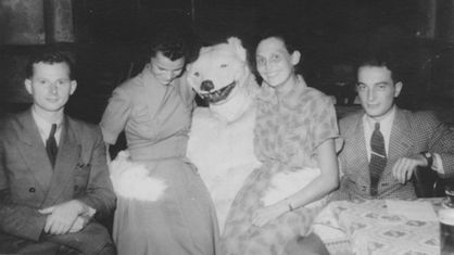 Zwei Frauen sitzen auf dem Schoß eines als Eisbär verkleideten Menschen. Zwei Männer sitzen daneben.