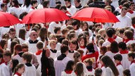 Teilnehmer an dem Abschlussgottesdienst mit roten Sonnenschirmen im RheinEnergiestadion