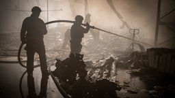 Einsatzkräfte löschen das Feuer in einer zerstörten Druckerei in Charkiw, Ukraine.