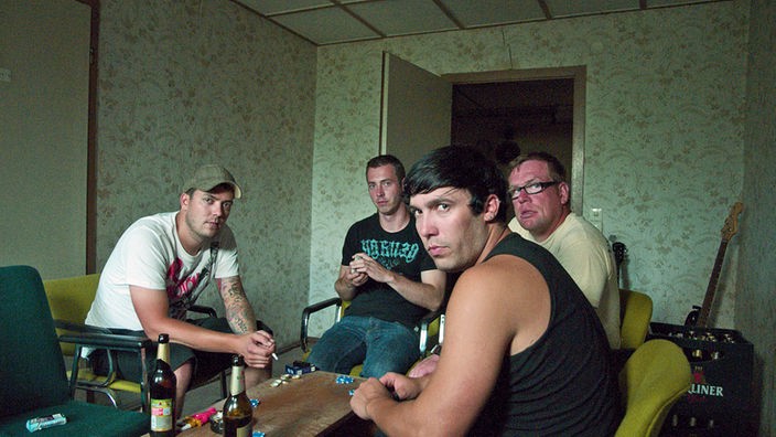 Vier Männer sitzen um einen Tisch und trinken Bier