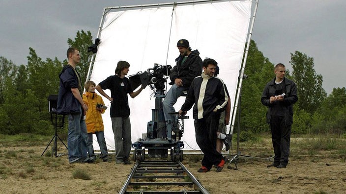 Filmteam vor einer weißen Stellwand