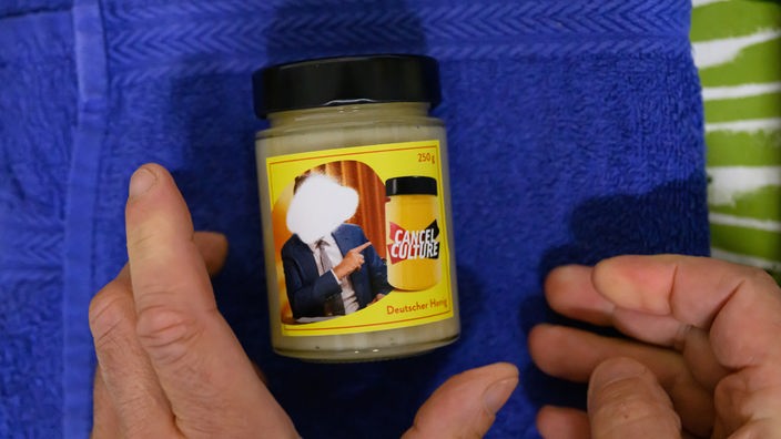 Ein Glas Honig der Marke „Cancel Culture“ von Imker Rico Heinzig wird von einem Mitarbeiter mit dem Etikett beklebt.
