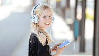 Portrait von einem Mädchen im Teenageralter mit Kopfhörer und Smartphone.
