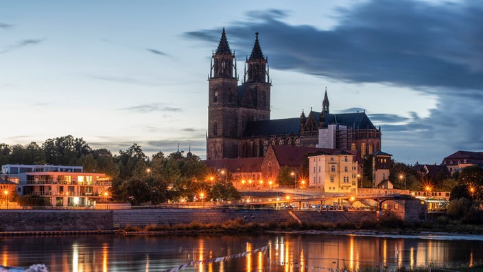 Die beiden Türme des Magdeburger Doms spiegeln sich in der Abenddämmerung im Wasser.