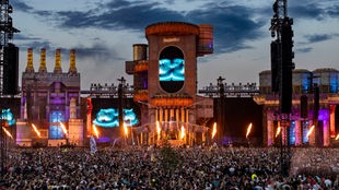 Archivaufnahme von 2023: Parookaville-Festival mit einer großen Bühne in der Dämmerung, davor zahlreiche Feiernde.