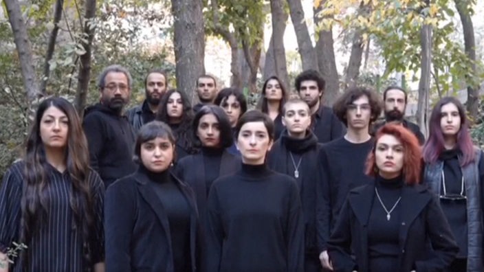 Screenshot eines Videos, das Soheila Golestani und weitere Schauspielerinnen ohne Kopftuch und einige Männer, alle in Schwarz gekleidet, zeigt.