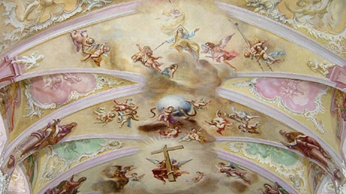 Die Decke der Stiege verziert mit Engeln, einem Kreuz und weiteren christlichen Motiven